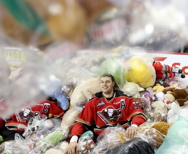 Calgary Hitmen Keegan Kanzig in a pile of bears during the annual Teddy Bear Toss at the Scotiabank Saddledome on December 6, 2015.