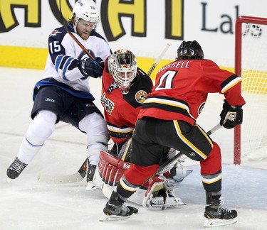 Winnipeg Jets Matt Halischuk, left, collides with Calgary Flames goalie Karri Ramo and Flames Kris Russell during their game at the Scotiabank Saddledome in Calgary on December 22, 2015.