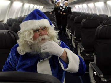 WestJet's Blue Santa took his seat after he loaded his sack onto the plane as he boarded it to fly from Halifax to Toronto for his next stop on Dec. 9, 2015.