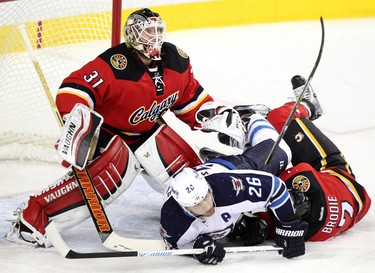 Calgary Flames TJ Brodie, right collides with Winnipeg Jets Blake Wheeler, middle, into Flames netminderKarri Ramo during their game at the Scotiabank Saddledome in Calgary on December 22, 2015.