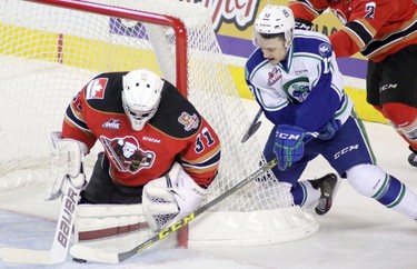 Calgary Hitmen netminder Cody Porter, left, blocks a shot from Swift Current Broncos Cavin Leth during the annual Teddy Bear Toss at the Scotiabank Saddledome on December 6, 2015.