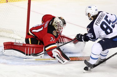 Calgary Flames goalie Karri Ramo, left, blocks a shot on net from Winnipeg Jets Mathieu Perreault during their game at the Scotiabank Saddledome in Calgary on December 22, 2015.