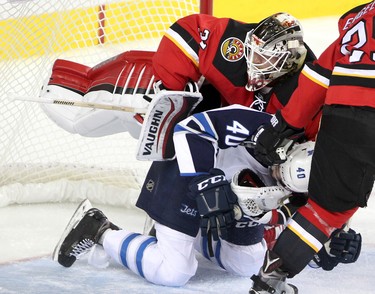 Winnipeg Jets Joel Armia , right, crashes into Calgary Flames goalie Karri Ramo during their game at the Scotiabank Saddledome in Calgary on December 22, 2015.