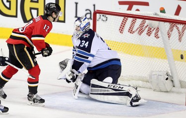 Calgary Flames Johnny Gaudreau, left, scores his second goal on Winnipeg Jets netminder Michael Hutchinson during their game at the Scotiabank Saddledome in Calgary on December 22, 2015.