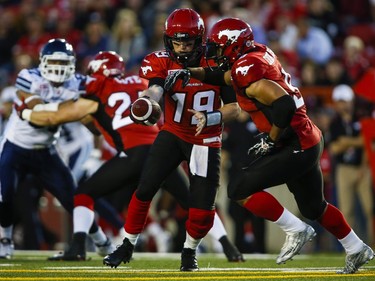 Calgary Stampeders quarterback Bo Levi Mitchell, centre, hands the ball off to Jon Cornish during second half CFL football action against the Toronto Argonauts in Calgary, Monday, July 13, 2015.