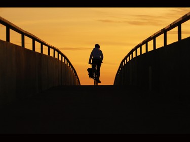 A cyclist rides over a pedestrian bridge across Deerfoot Trail at dusk on Monday Oct. 5, 2015.