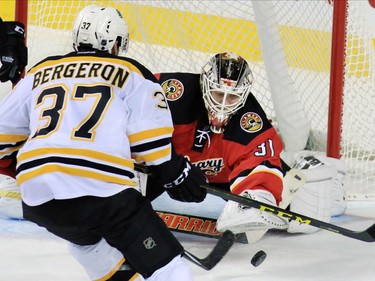 The Calgary Flames' Karri Ramo stops this shot as the Boston Bruin's Patrice Bergeron moves in for the rebound during the second period of NHL action at the Scotiabank Saddledome on Friday December 4, 2015.