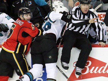 The Calgary Flames' Mark Giordano and San Jose Sharks Tomas Hertl pile up with an official in the second period of NHL action against the at the Scotiabank Saddledome on Tuesday December 8, 2015.