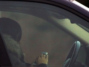 A person uses a cell phone while stopped at a red light at Elbow Drive and Southland Drive S.W. on Thursday, Dec. 10, 2015.