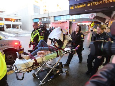 An injured passengers with their head covered is transported by Calgary EMS crews after the Shanghai to Toronto Air Canada flight experienced severe turbulence.