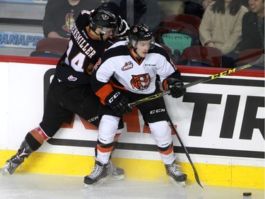 Hitmen Layne Bensmiller, 14, tries to dig the puck away from Tigers Brad Forrest, 2,  as the Calgary Hitmen hosted the Medicine Hat Tigers in Western Hockey League action at the Saddledome on Saturday, December 19, 2015.