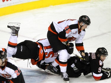 Hitmen Pavel Karnaukhov, 9, ends up on the bottom on a pile with Tigers Connor Clouston, 25, and Ty Schultz, 15, as the Calgary Hitmen hosted the Medicine Hat Tigers in Western Hockey League action at the Saddledome on Saturday, December 19, 2015.
