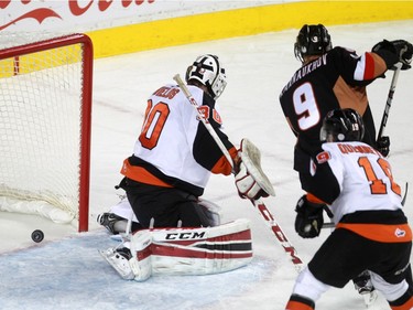 The puck trickles past Tigers goalie Mack Shield and teammate David Quenneville as Hitmen Pavel Karnaukhov, 9, provides a screen the Calgary Hitmen hosted the Medicine Hat Tigers in Western Hockey League action at the Saddledome on Saturday, December 19, 2015.