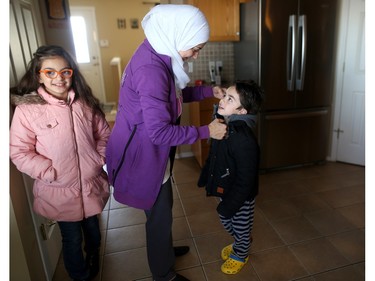Nour bundles up her son Faisal, 6, before going out to play in the snow.