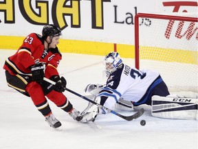 Calgary Flames Sean Monahan, left, takes a shot on Winnipeg Jets netminder Michael Hutchinson during their game at the Scotiabank Saddledome in Calgary on December 22, 2015.