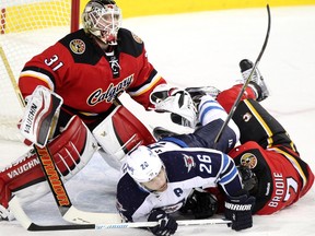 Calgary Flames defenceman TJ Brodie, right collides with Winnipeg Jets Blake Wheeler, middle, into Flames netminder Karri Ramo during their game at the Scotiabank Saddledome in Calgary on December 22, 2015.