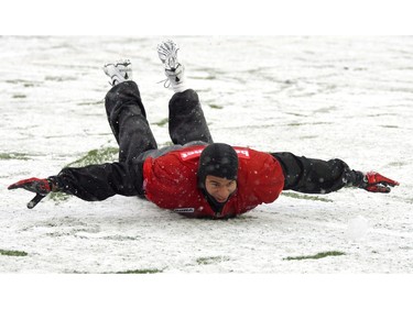 Stampeders' Jon Cornish goes for a slide following a snow covered team training session at McMahon Stadium on October 15, 2010.