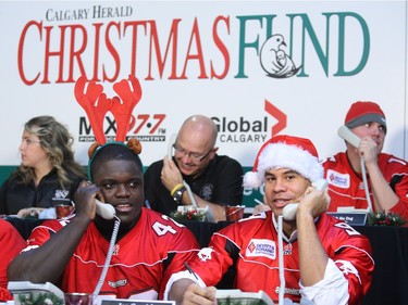 Calgary Stampeders Mike Labinjo and right Jon Cornish help out to man the phones during The Give us a Jingle telethon.