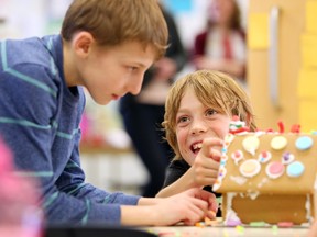 McKenzie Towne School Grade 4 student Tyler Beveridge, right, told classmate Keilan Popowich where to place more candy as they helped to build a gingerbread house on December 7, 2015. The students at the school were putting together the houses to be auctioned off to help raise money for Habitat for Humanity.
