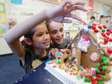 McKenzie Towne School Grade 4 students Ana Kongsuwan, left, and Riley Croteau took a closer look at one of the gingerbread houses their class built on December 7, 2015. The students at the school were putting together the houses to be auctioned off to help raise money for Habitat for Humanity.