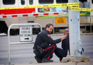 A police officer comforts a witness at the scene of a fatal C-Train collision near the Sunridge station in northeast Calgary on October 22, 2015.