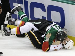 Calgary Flames defenceman Dennis Wideman and Dallas Stars left wing Patrick Sharp fall to the ice as they fight during the second period on Thursday.