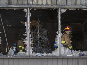 Firefighters check out the interior damage to a house at the corner of Fairmount Drive S.E. and Flavelle Road SE in Calgary, on December 15, 2015, after a fire ravaged the building. Two cats were killed, and one man was sent to hospital with potentially life-threatening injuries.