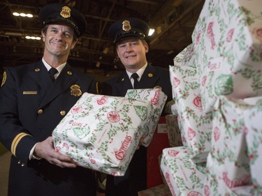 Keith Stahl, captain, right, and Phil Watson, training officer, stand with one of the many giant piles of presents at the annual Calgary Firefighters Toy Association party, at the Stampede Corral in Calgary, on December 20, 2015.