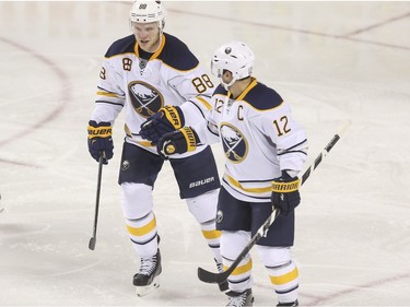 Buffalo Sabres Brian Gionta, 12, and Jamie McGinn bump fists after a goal against the Calgary Flames at the Saddledome in Calgary, on December 10, 2015.