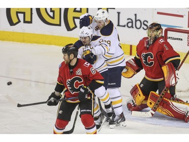 Calgary Flames goalie Jonas Hiller and defense Dennis Wideman and Buffalo Sabres Brian Gionta, 12, and Zemgus Girgensons, 28, watch as the puck comes flying in during game action at the Saddledome in Calgary, on December 10, 2015.