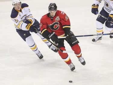 Calgary Flames Sean Monahan fights off some hooks from Buffalo Sabres Jack Eichel during game action at the Saddledome in Calgary, on December 10, 2015.