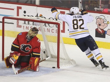 Calgary Flames goalie Jonas Hiller looks defeated as Buffalo Sabres Marcus Foligno cheers for the goal scored during game action at the Saddledome in Calgary, on December 10, 2015.