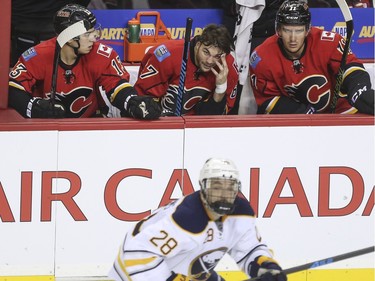Calgary Flames Johnny Gaudreau, left, Mikael Backlund, right, don't look pleased as Michael Frolik holds a cotton ball to his cut after receiving a check from behind from Buffalo Sabres Cody Franson during third period action at the Saddledome in Calgary, on December 10, 2015.