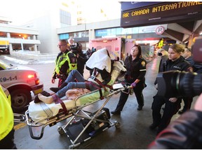 An injured passenger with their head covered is transported by Calgary EMS crews after the Shanghai to Toronto Air Canada flight experienced severe turbulence.