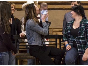 Kaiden Viney, 7 months, gets a kiss Michelle Morgan (Lou Fleming), as he and his mom Amy Davidson, right, get their photos taken with some of the cast of CBC's hit TV show, Heartland, including Amber Marshall (Amy Fleming), Graham Wardle (Ty Borden),  Shaun Johnston (Jack Bartlett), Jessica Steen (Lisa Stillman), and Alisha Newton (Georgie), in support of HomeFront's 'Cool It, Calgary' campaign at the Symons Valley Ranch market in Calgary, on December 12, 2015.