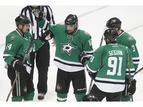Dallas Stars left wing Jamie Benn (14) is congratulated by teammates Patrick Sharp (10), John Klingberg (3), and Tyler Seguin (91) after scoring a goal against Vancouver Canucks goalie Ryan Miller during the first period of an NHL hockey game Friday, Nov. 27, 2015, in Dallas.