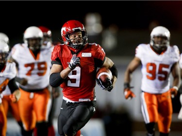 BC Lions' players look on as Calgary Stampeders' Jon Cornish, centre, runs the ball during second half CFL football action in Calgary on Oct. 11, 2013.