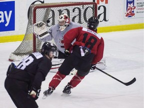 Mason McDonald gloves at a puck fired from Mathew Barzal during a Canadian World Junior Hockey team practice, in Toronto earlier this month. McDonald, a Flames prospect, has a chance to seize the crease for Team Canada in Finland.