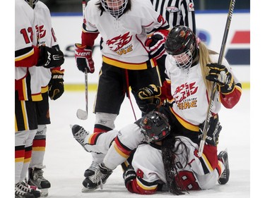 Tianna Ko of the Calgary Fire falls to the ice while celebrating her third period goal against the Edmonton Thunder with teammates Chantal Ricker, 22, top, and Isabel Johnson, 9, in the opening female division game at the annual Macs Midget Tournament Boxing Day morning December 26, 2015 at Max Bell Arena.