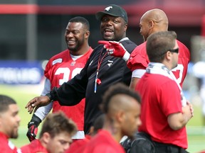 Calgary Stampeders defensive co-ordinator DeVone Claybrooks, centre, talks with players Charleston Hughes, left, and Juwan Simpson, right, in his duties as D-line coach last July. He's excited for his new responsibilities after being officially announced as the man in charge of the Stamps' D next season.