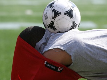 RB Jon Cornish successfully  holds a soccer ball on his back while taking off his jersey at practice on Saturday.  The Calgary Stampeders did a walk through practice on June 19, 2010 as they prepared for a preseason game.