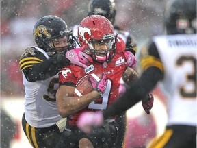 Calgary Stampeder running back Jon Cornish tries to shake off a tackle by Hamilton Ti-Cat lineman Greg Peach in the first quarter at McMahon Stadium Saturday evening October 20, 2012.