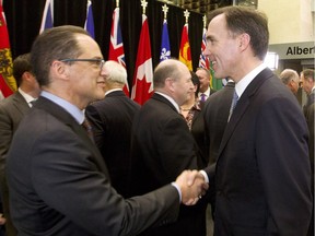 Federal Finance Minister Bill Morneau, right, shakes hands with Alberta Finance Minister Joe Ceci at the conclusion of a federal, provincial and territorial finance meeting in Ottawa on Dec. 21, 2015.