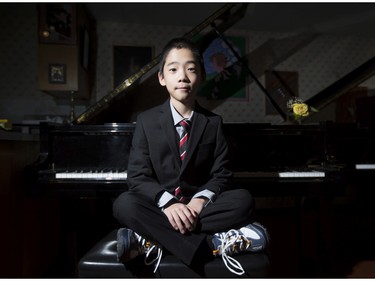 Kevin Chen, a nine year-old piano prodigy, poses for a photo at a piano with his suit and sneakers in Calgary, on February 3, 2015.