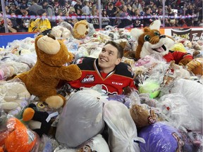 Calgary Hitmen Radel Fazleev jumps into a mound of teddy bears after scoring the first goal during the annual Teddy Bear toss game against the Moose Jaw Warriors at the Scotiabank Saddledome in Calgary on December 7, 2014.