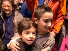 A young member of the Abbara family, left, is welcomed by another young Calgarian at the Calgary International Airport in Calgary.