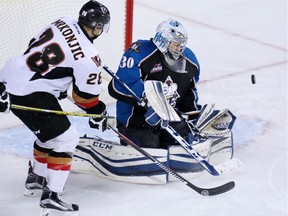 The Calgary Hitmen's Tyler Mrkonjic looks for a rebound in front of Kootenay Ice goaltender Wyatt Hofflin during first period WHL action at the Scotiabank Saddledome on Monday December 28, 2015.