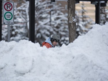 Rose-Anna Balez shovels snow behind a giant snow pile to clear around Olympic Plaza after a big overnight snowfall in Calgary, on December 16, 2015.