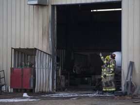 Firefighters examine the damage after a propane tank explosion injured three people at Hennessey Welding Ltd at 11500 114 Ave SE in Calgary, on December 2, 2015.