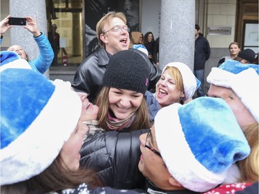 Laureen Bryant, centre, gets a group hug from WestJetters after winning the WestJet coin toss free flight competition on Stephen Ave in Calgary, on Dec. 9, 2015. This was part of WestJet's day of mini miracles and ended with Bryant winning a flight for two anywhere WestJet flies.